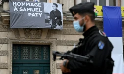 Un policier devant un portrait de Samuel Paty affiché sur la façade de l'Opéra Comédie à Montpellier le 21 octobre 2020, cinq jours aprÚs son assassinat