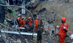 Des sauveteurs recherchent des survivants dans les ruines d'un bâtiment, à Mamuju, sur l'île des Célèbes en Indonésie, le 15 janvier 2021