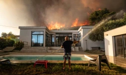 Un homme tente de maitriser le feu avant d'être évacué de sa maison à La Couronne, près de Marseille le 4 août 2020 où un violent incendie ravage l'ouest de la ville