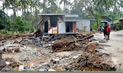 Des Indiens regardent une habitation détruite par un glissement de terrain dans le village de Kannapanakundu, dans l'Etat du Kerala (sud), le 18 août 2018