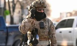 Un agent de la police aux frontières américaine devant des manifestants à Minneapolis, près du lieu où des agents fédéraux ont tué un homme par balle, le 24 janvier 2026