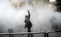 Une Iranienne lève le poing dans la fumée des gaz lacrymogènes lors d'une manifestation à Téhéran, le 30 décembre 2017