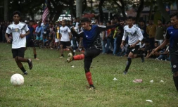 Un Rohingya de l'équipe Cheras Harimau frappe la balle tandis que des joueurs de Selangor (en blanc) le regardent lors d'un tournoi destiné aux réfugiés, à l'occasion des célébrations de la fin du ramadan en Malaisie, à Kuala Lumpur, le 18 juin 2018