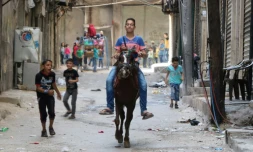 Un garçon syrien monte un cheval dans les rues d'Alep et des enfants jouent lors de l'AĂŻd au premier jour de la trĂȘve, le 13 esptembre 2016