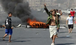 Un Yéménite fait le "V" de la victoire en passant près de pneus incendiés lors de manifestations contre l'inflation et le coût de la vie, à Aden, dans le sud du Yémen, le 8 septembre 2018