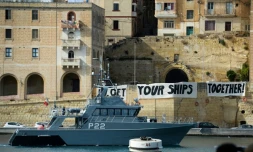Un bateau des gardes-cĂŽtes maltais patrouillent dans la baie de Birgu Ă Malte, devant des banderoles oĂč l'on peut lire "Get your ships together", le 23 septembre 2019