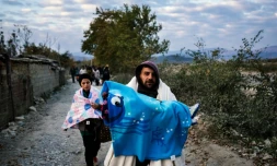 Un homme porte son enfant alors qu'il vient avec d'autres migrants de passer la frontière gréco-macédonienne près de Gevgelija, en Macédoine, le 15 novembre 2015