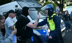 Des manifestants font face à un policier lors d'un rassemblement dans le centre d'Epping, au nord-est de Londres, le 20 juillet 2025