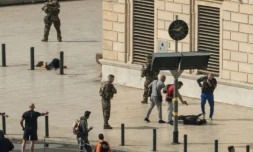 Un policier pointe son arme sur un homme au sol à quelques mètres du corps d'une victime d'une attaque à la gare Saint-Charles de Marseille le 1er octobre 2017