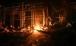 Des pompiers luttent contre un incendie provoqué par un bombardement russe sur un entrepôt de la compagnie des postes Nova Pochta dans un village près de Kharkiv, le 13 janvier 2026 en Ukraine