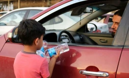 Un garçon irakien essaye de vendre des bouteilles d'eau dans une rue de Mossoul, oĂč des enfants orphelins errent pour mendier ou vendre des objets futiles pour survivre, un an aprĂšs la reprise par l'armĂ©e irakienne de la ville aux jihadistes, le 7 juillet 2018