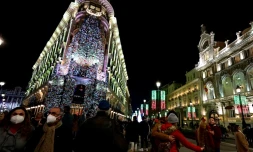 Des passants déambulent masqués dans les rues illuminées de Madrid, le 22 décembre 2021 au lendemain de l'annonce du retour du masque obligatoire à l'extérieur en Espagne