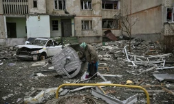 Une femme âgée se tient au milieu des gravats près d'un immeuble endommagé à Kharkiv en Ukraine, le 27 mars 2022