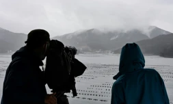 Des personnes observent des volutes de fumée s'échappant d'une montagne, près de la ville d'Ofunato, dans la région japonaise d'Iwate, le 5 mars 2025 