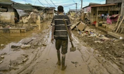 Un homme marche dans une rue couverte de boue après une crue soudaine qui a frappé la région d'Aceh Tamiang, dans la province d'Aceh, sur l'île indonésienne de Sumatra, le 6 décembre 2025
