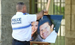 Un officier de police tient le 20 juin 2016 à Pézénas dans l'Hérault une photographie de Jessica Schneider et Jean-Baptiste Salvaing, victimes d'un assassinat jihadiste à Magnanville, le 13 juin 2016