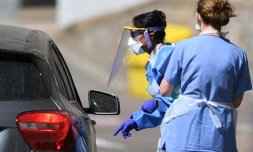 Des soignantes s'entretiennent avec un automobiliste à propos des kits de dépistage au Covid-19, le 25 avril 2020 à Londres