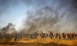 Des manifestants palestiniens se protègent des gaz lacrymogènes israéliens pendant une manifestation à Jabalia, au centre de la bande de Gaza, le 8 juin 2018