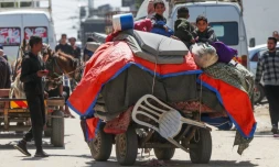 Des enfants palestiniens assis sur leurs affaires, rassemblées dans une charrette à cheval, à Nousseirat (centre de la bande de Gaza), le 12 avril 2024