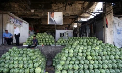 Des négociants syriens près du portrait du président Bachar al-Assad au marché des Halles de Damas, le 21 septembre 2015