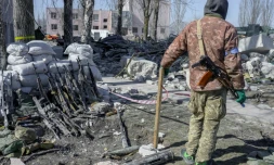 Un soldat ukrainien garde des fusils de soldats morts et blessés près de la caserne touchée la veille par des roquettes russes, à Mykolaïv, dans le sud de l'Ukraine, le 19 mars 2022.