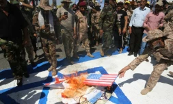 Sur cette photo d'archive, des combattants chiites irakiens des brigades du Hezbollah brûlent des drapeaux américains et israéliens durant un défilé militaire à Bagdad, le 31 mai 2019