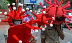 Des policiers portant des déguisements sur le thÚme du coronavirus, pour inciter les habitants à respecter les restrictions sanitaires, sont postés à un carrefour de Hyderabad (Inde), le 27 mai 2021