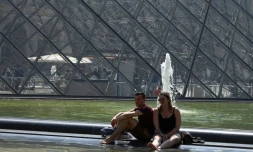 Des touristes se rafraĂźchissent dans un bassin devant la Pyramide du Louvre le 26 juin 2019