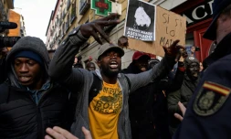 Des manifestants face à des policiers dans un quartier de Madrid, le 16 mars 2018, au cours d'un rassemblement à la mémoire d'un vendeur des rues sénégalais 