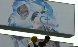 Des passants devant une affiche annonçant la visite papale, le 27 avril 2017 au Caire