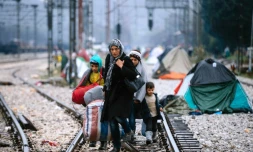 Une femme et trois enfants marchent sur des rails reliant la GrÚce à l'Europe de l'ouest, à la frontiÚre gréco-macédonienne prÚs du village grec d'Idomeni, le 9 mars 2016