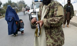 Un femme passe à cause d'un combattant taliban à Jalalabad, Afghanistan, le 12 décembre 2021