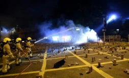 Des pompiers interviennent pour éteindre le feu sur des barricades bloquant une route près de l'université polytechnique de Hong Kong 