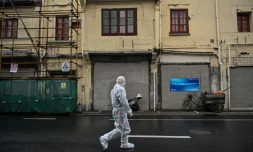 Un employĂ© revĂȘtu d'une combinaison protectrice marche prĂšs d'un quartier confinĂ© en raison d'une flambĂ©e de cas de coronavirus Ă Shanghai le 17 mars 2022