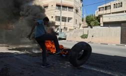 Un manifestant palestinien pousse un pneu dans une rue du village de Borqui, près de Jénine, le 26 septembre 2021 en Cisjordanie