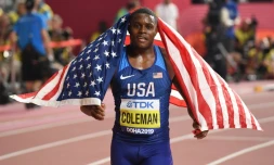 Le sprinteur américain Christian Coleman s'enroule dans le drapeau national aprÚs avoir gagné la finale du 100 m aux Mondiaux d'athlétisme, le 28 septembre 2019 à Doha