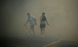 Des habitants se protègent des fumées lors d'un incendie de forêt à Mazagon, près d'un parc naturel dans le sud-ouest de l'Espagne, le 25 juin 2017 