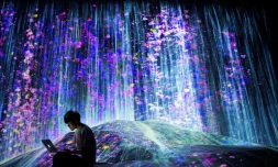 Un membre du collectif japonais teamLab prĂšs d'une cascade de lumiĂšre au Mori Building Digital Art Museum, le 1er mai 2018 Ă Tokyo
