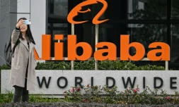 Une passante prend un selfie devant le logo d'Alibaba dans le quartier de Xuhui à Shanghai, le 22 février 2025