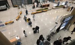 Des employés en tenue de protection guident les voyageurs le 30 novembre 2021 dans le hall des arrivées de l'aéroport international d'Incheon, en Corée du Sud