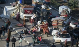 Des déplacés palestiniens  attendent près du passage de Netzarim, qui coupe la bande de Gaza en deux, avant de pouvoir regagner le nord du territoire, le 26 janvier 2025
