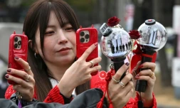 Des fans prennent des photos de bâtons lumineux à l'effigie de BTS à leur arrivée au stade où le groupe de K-pop se produira, à Goyang, le 9 avril 2026