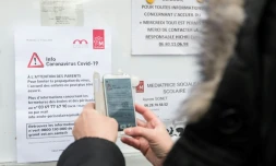 Une femme regarde un panneau d'information sur le coronavirus à Mulhouse à l'entrée d'une école, le 6 mars 2020