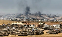 Des tanks et des bulldozers israéliens déployés à la lisière de la bande de Gaza, d'où s'élève de la fumée de bâtiments détruits par des frappes israéliennes, le 17 mai 2025