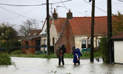 Des personnes marchent dans une rue inondée au Doulac, prÚs de Saint-Omer, le 14 novembre 2023, dans le Pas-de-Calais