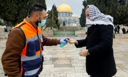Un volontaire propose du gel hydroalcoolique à un palestinien en route pour la prière du vendredi, devant la mosquée Al-Aqsa à Jérusalem, le 20 mars 2020