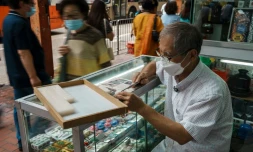 L'artisan Cheung Shun-king grave des caractères chinois sur des tuiles de mah-jong dans son échoppe du quartier de Yau Tsim Mong, le 6 juillet 2022 à Hong Kong