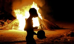 Un habitant tape sur une casserole devant un feu allumé lors d'une protestation contre les coupures de courant et les pénuries d'énergie à La Havane, le 14 mai 2026 à Cuba
