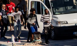 Vingt-sept migrants mineurs non-accompagnĂ©s, secourus par le navire de l'ONG espagnole Proactiva Open Arms, sont conduits vers des vĂ©hicules de la police italienne avant de quitter le port de Lampedusa oĂč ils ont dĂ©barquĂ© le 17 aoĂ»t 2019