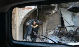 Un membre des Casques blancs syriens transporte un blessé après un bombardement du régime sur la ville de Hammouriyé, le 7 mars 2018 dans la Ghouta orientale